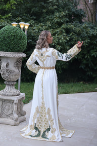 Une femme élégante portant un caftan marocain de luxe, avec des motifs complexes et des couleurs éclatantes.