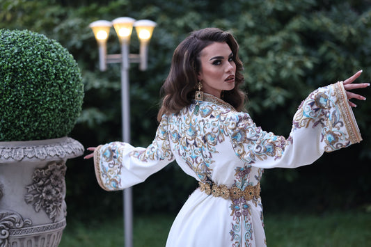 Une femme élégante portant un caftan marocain de luxe, avec des motifs complexes et des couleurs éclatantes..